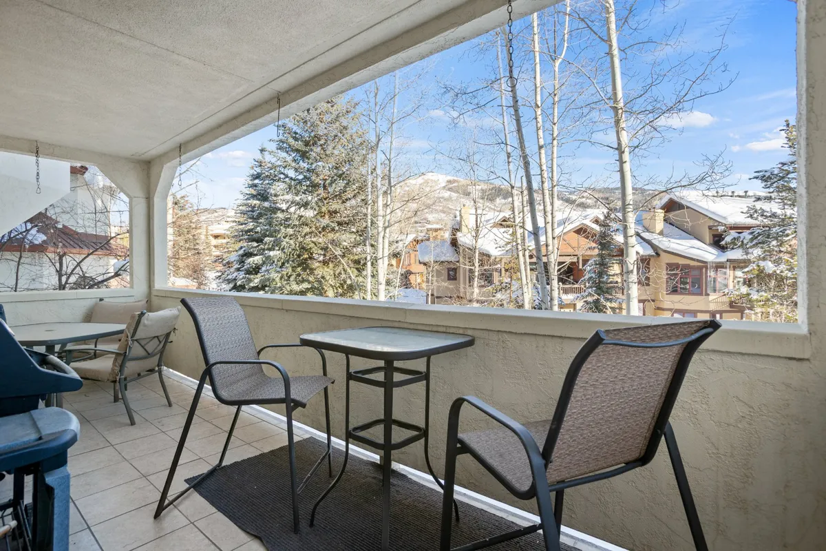 The image showcases a balcony furnished with a table and chairs, overlooking a snowy landscape and surrounded by trees. This tranquil setting highlights the opportunity for guests to enjoy meals, coffee, or quiet moments together while taking in beautiful outdoor views.