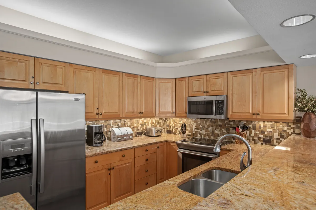 A modern kitchen with stainless steel appliances, granite countertops, and warm wood cabinetry. The layout is open and inviting—ideal for meal preparation or enjoying time with family and friends.