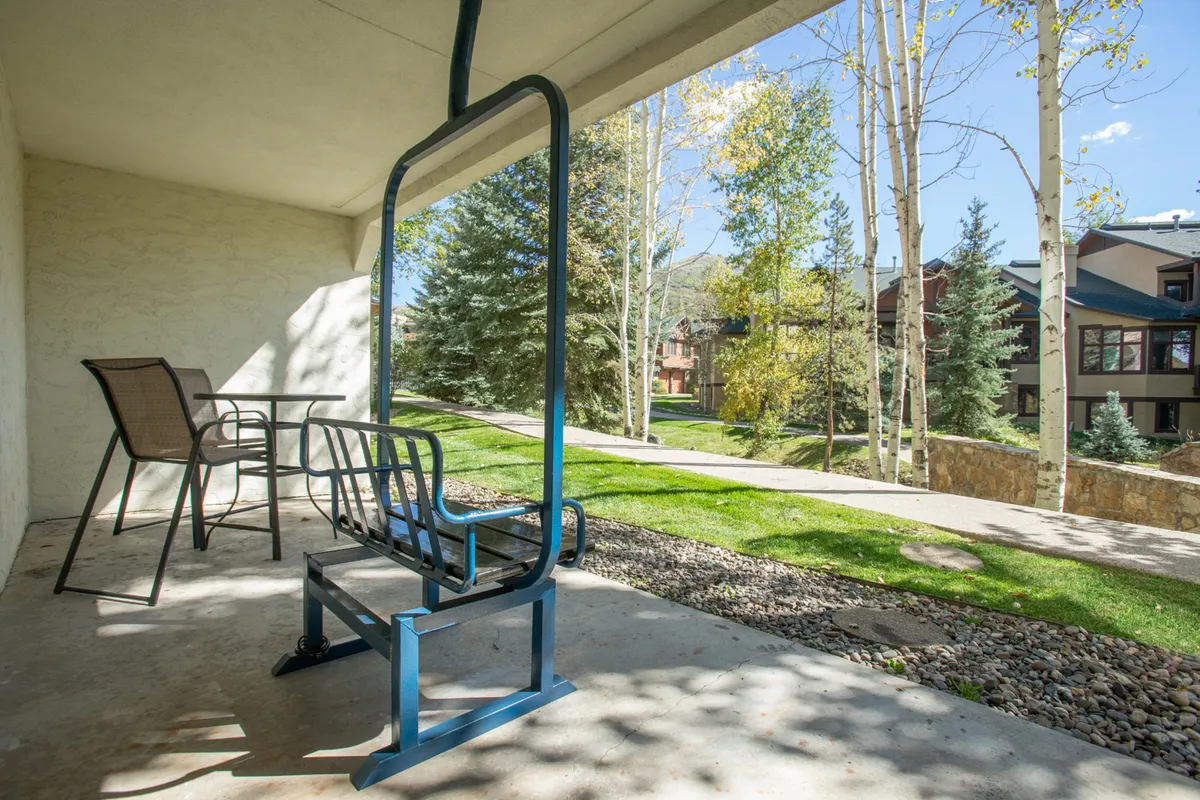 An inviting outdoor seating area set along a pathway, framed by surrounding trees. The atmosphere is tranquil and encourages relaxation or social connection while enjoying the natural landscape.